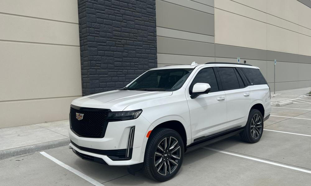 White 2023 Cadillac Escalade parked outside a modern building